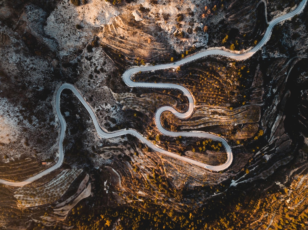 Aerial view of a winding road snaking through a mountainous landscape with fields and trees. Bath Digital Marketing Agency