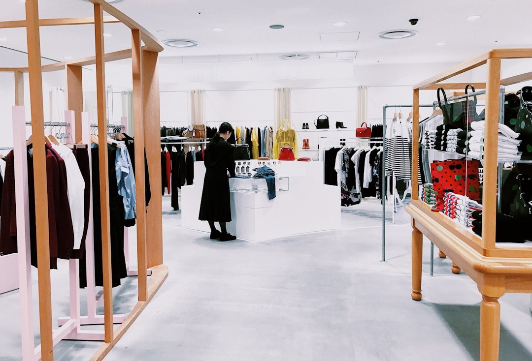 Interior of a modern clothing store featuring racks of apparel and a customer browsing, with a stylish and minimalist design. Bath Digital Marketing Agency