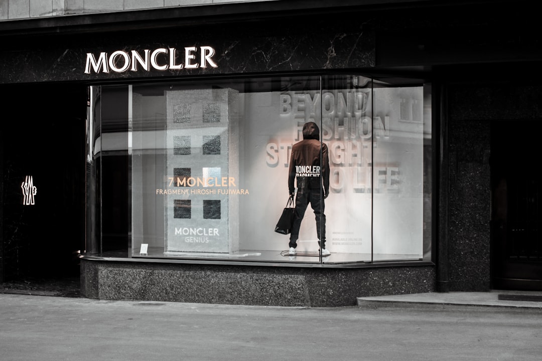 A fashion store window display featuring a mannequin dressed in Moncler attire, with promotional text "BEYOND FASHION STRAIGHT TO LIFE" in the background. Bath Digital Marketing Agency