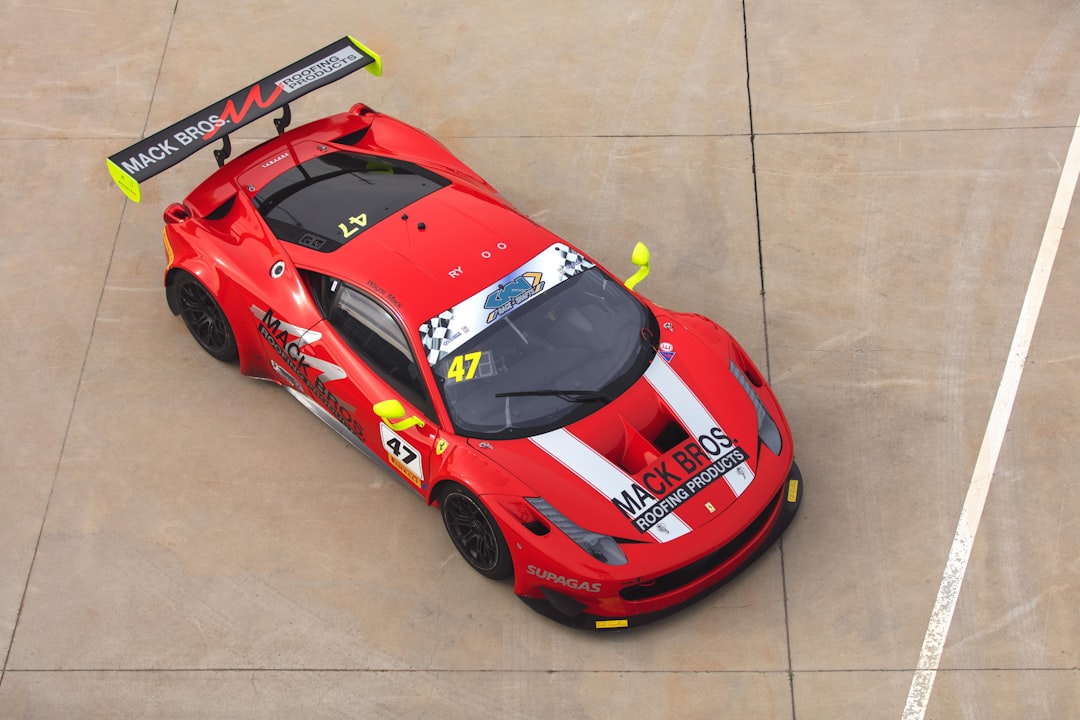 A red racing car with a prominent rear wing and sponsor logos, viewed from above, parked on a concrete surface.  Bath Digital Marketing Agency