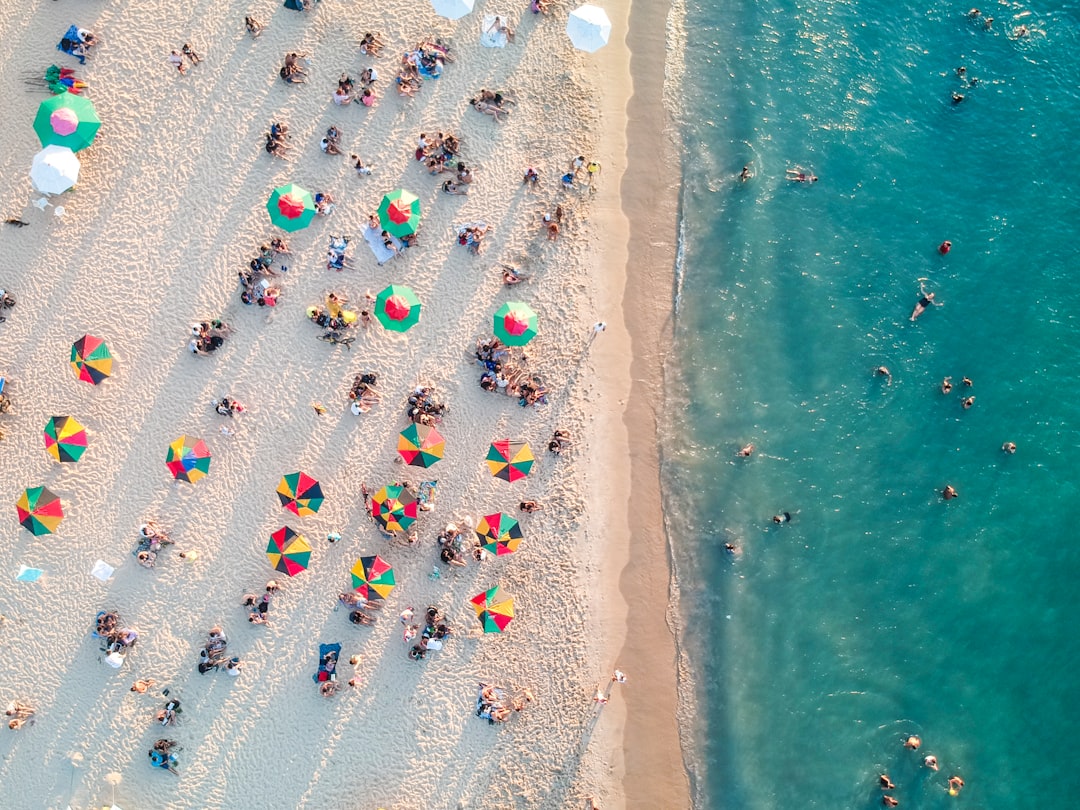 Aerial view of a crowded beach with colourful umbrellas and people swimming in the ocean Bath Digital Marketing Agency
