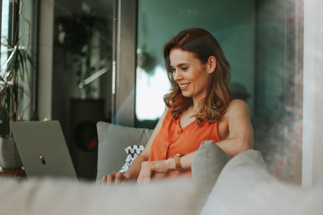 Smiling woman working on a laptop while seated comfortably on a sofa in a bright, modern space. Bath Digital Marketing Agency