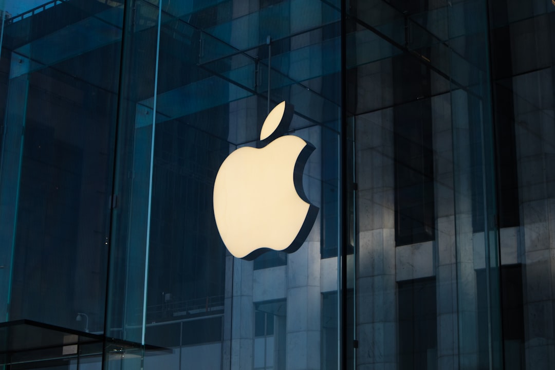 Illuminated Apple logo displayed on a glass storefront, with a modern building reflecting in the background. Bath Digital Marketing Agency