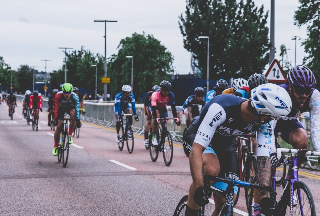 A group of cyclists competing in a race on a road, with various riders in colourful jerseys and helmets, surrounded by trees and street signs.  Bath Digital Marketing Agency