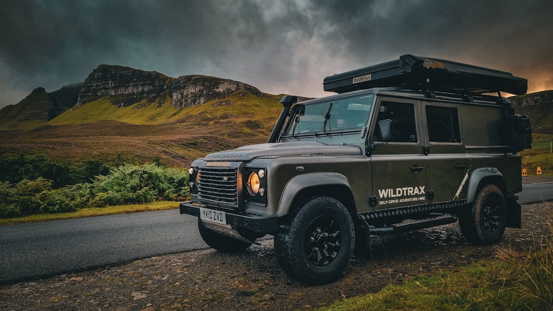 A rugged off-road vehicle parked on a road near mountainous terrain, with dark clouds overhead and lush greenery surrounding the area. Bath Digital Marketing Agency
