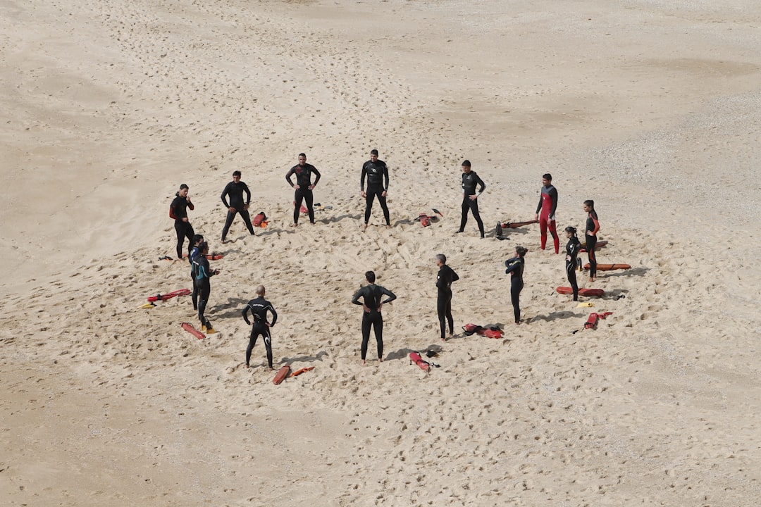 A group of surfers in wetsuits gathered in a circle on the beach, with surfboards laid out around them. Bath Digital Marketing Agency