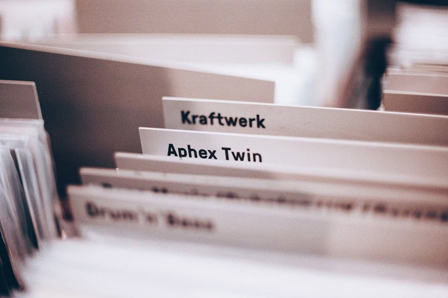 Close-up of music genre labels in a filing system, featuring "Kraftwerk" and "Aphex Twin" among others. Bath Digital Marketing Agency