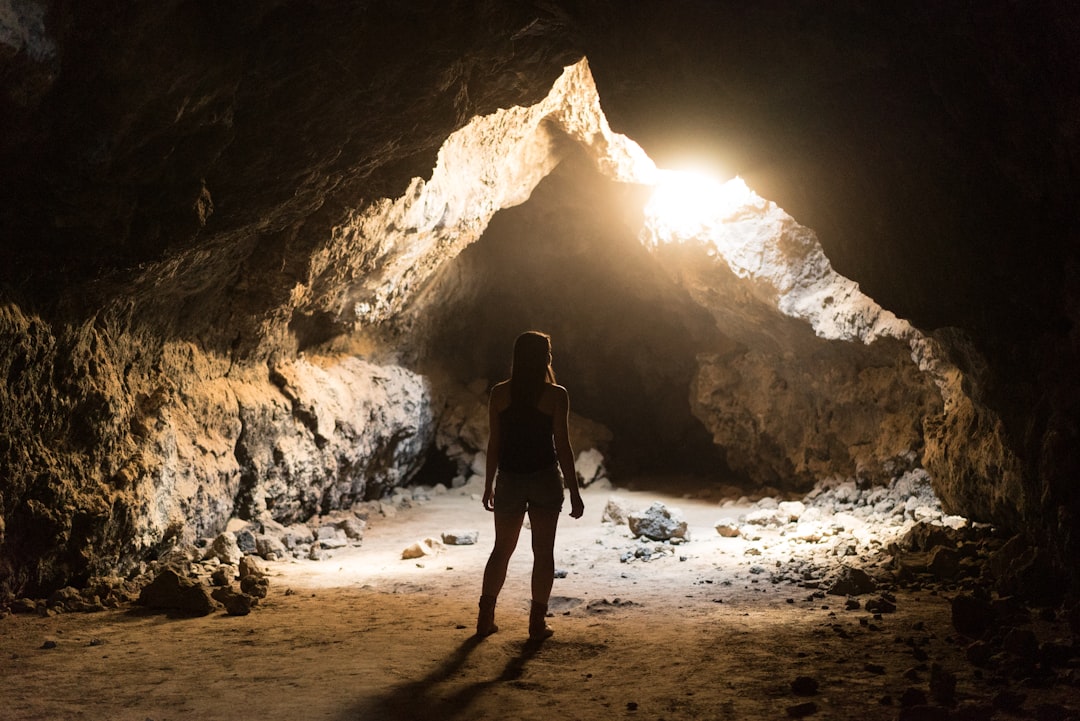 A silhouette of a person standing inside a cave, illuminated by a bright light coming from an opening, highlighting the rocky textures of the cave walls Bath Digital Marketing Agency.