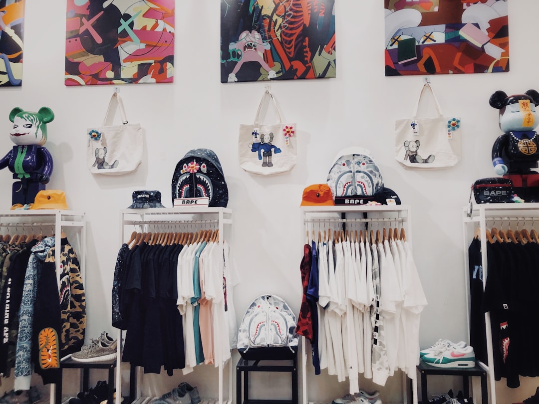 A clothing display featuring various t-shirts and bags hung on racks against a white wall adorned with colourful artwork. Bath Digital Marketing Agency