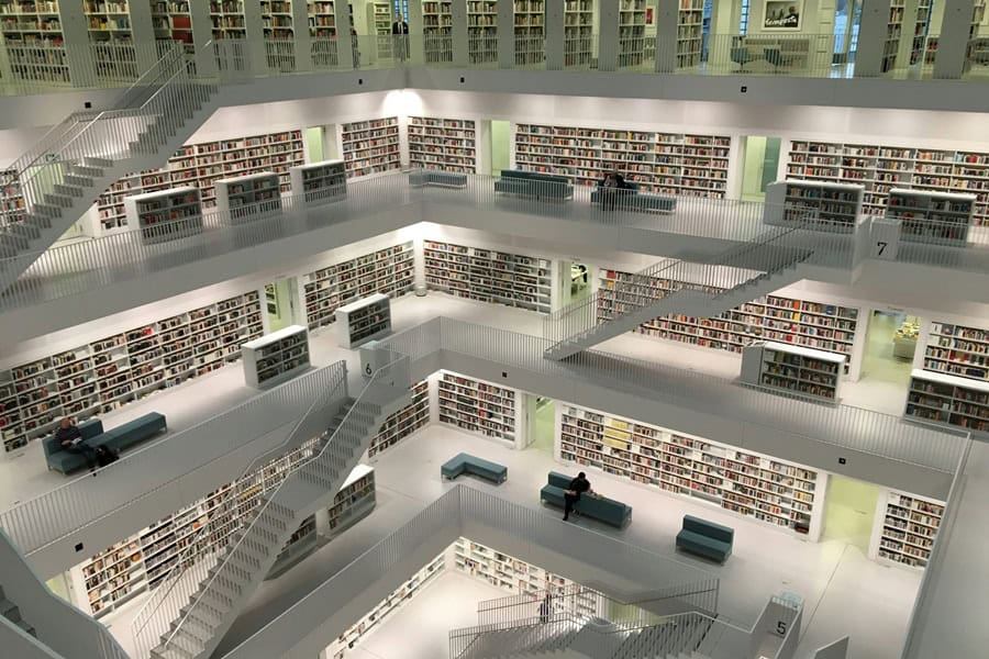 Aerial view of a modern library interior with multiple levels, featuring shelves filled with books and seating areas, showcasing a spacious and minimalist design. Bath Digital Marketing Agency