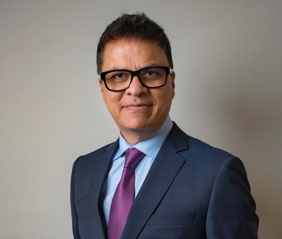 Wood table with porcelain mug, leather journal, brass pen, leather key ring, and a houseplant.
