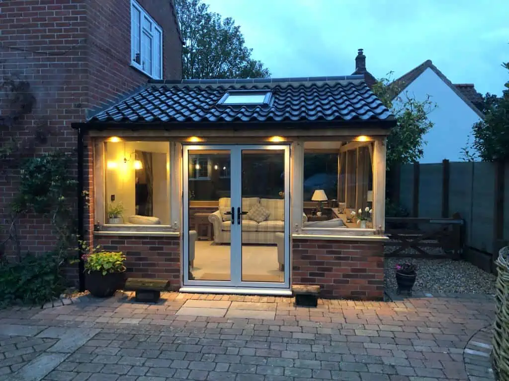 Wood table with porcelain mug, leather journal, brass pen, leather key ring, and a houseplant.