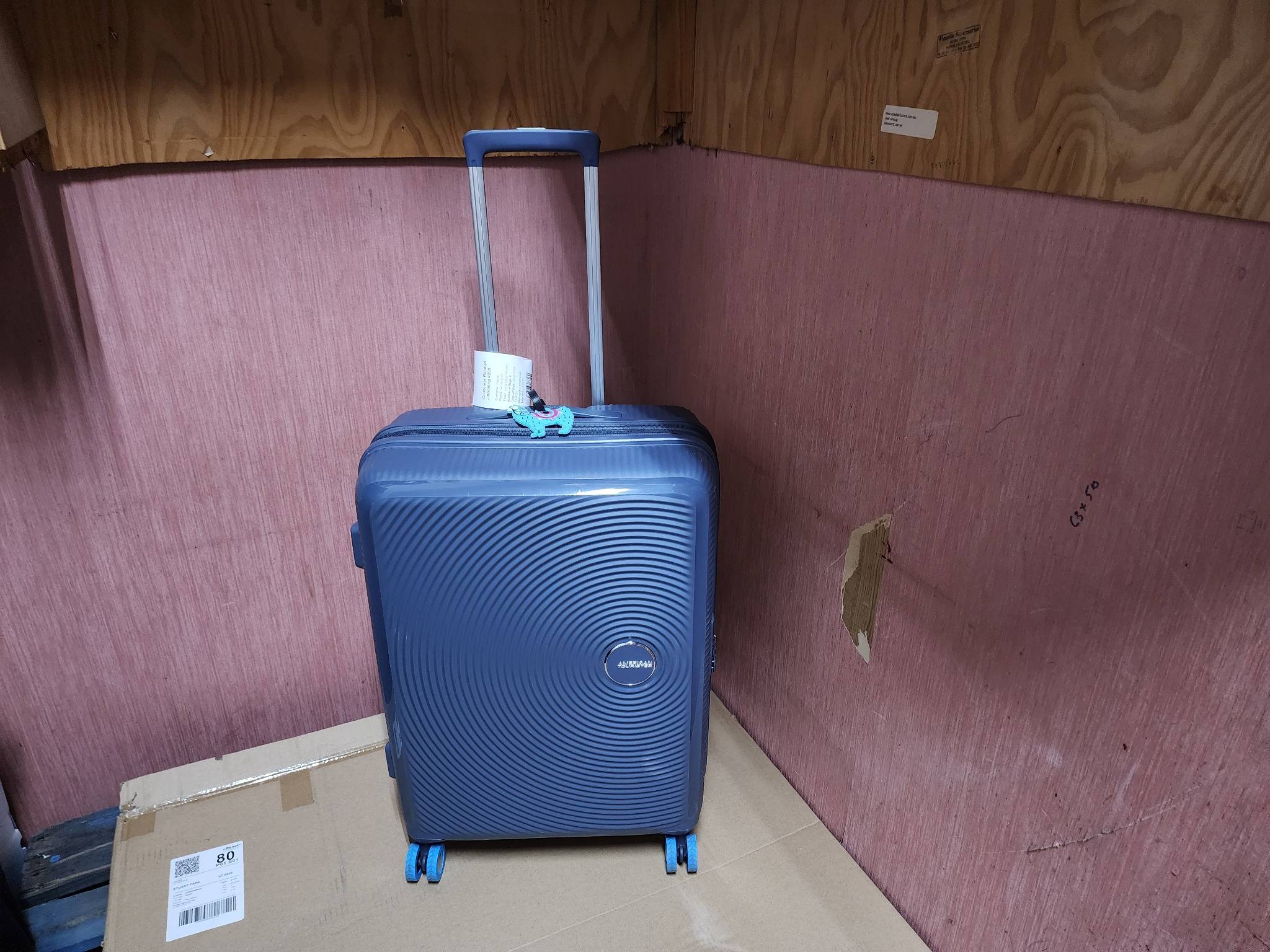 A blue hard-shell suitcase stored upright in a secure luggage locker area at Luggage Locker Darwin.