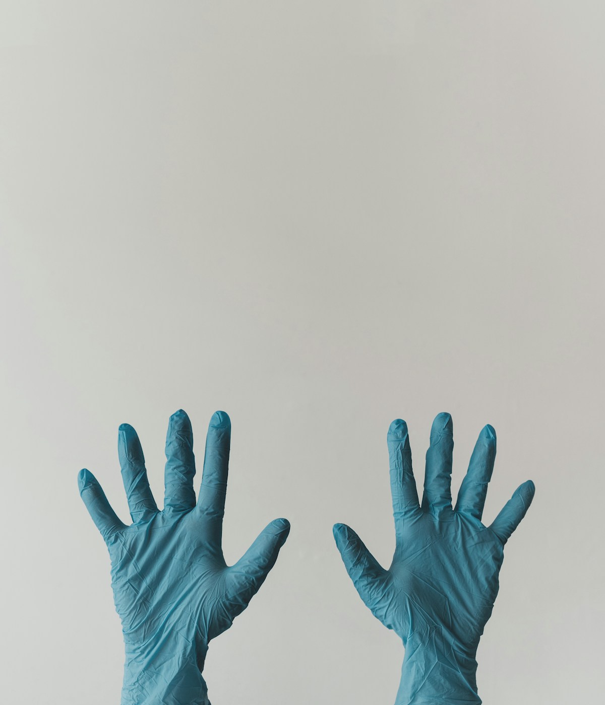 Two hands wearing blue latex gloves against a plain white background.