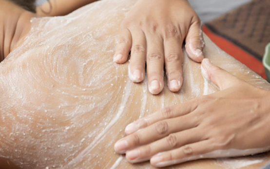 Hands applying exfoliating body scrub to smooth and refresh a client’s skin during the Baby Skin treatment at ViyUla Beauty Spa in Darwin.