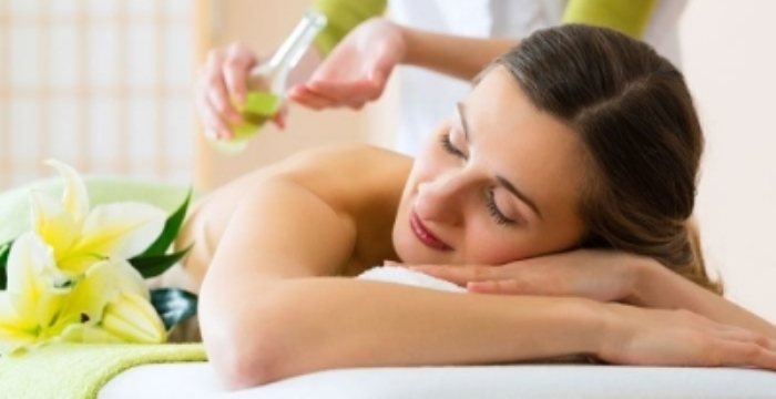 A relaxed woman receiving an aromatherapy massage at ViyUla Beauty Spa in Darwin, surrounded by flowers and soft lighting, promoting relaxation and wellbeing.