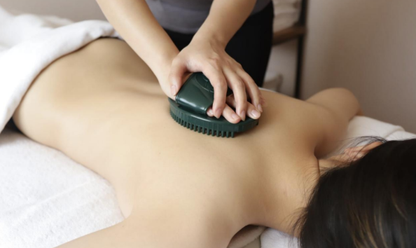 A woman receiving a scorpion massage treatment at ViyUla Beauty Spa in Darwin, using a heated jade tool to promote blood flow and relaxation.