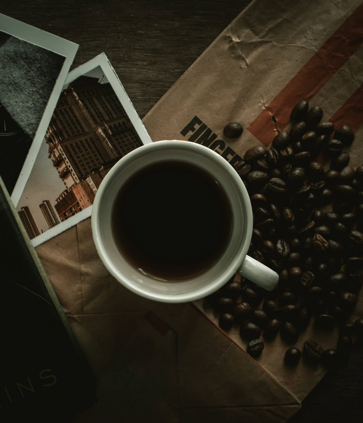 Overhead shot of a black coffee cup, scattered coffee beans, and two city photos, potentially for Beann artisan coffee marketing materials - beann speciality coffee
