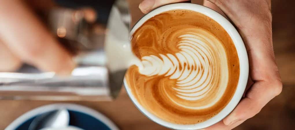 Barista pouring latte art into a cup of Beann artisan coffee - beann speciality coffee