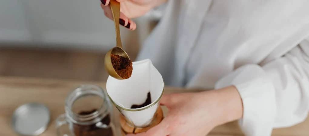 Person using gold scoop to add Beann artisan coffee grounds to a pour-over filter -  beann speciality coffee