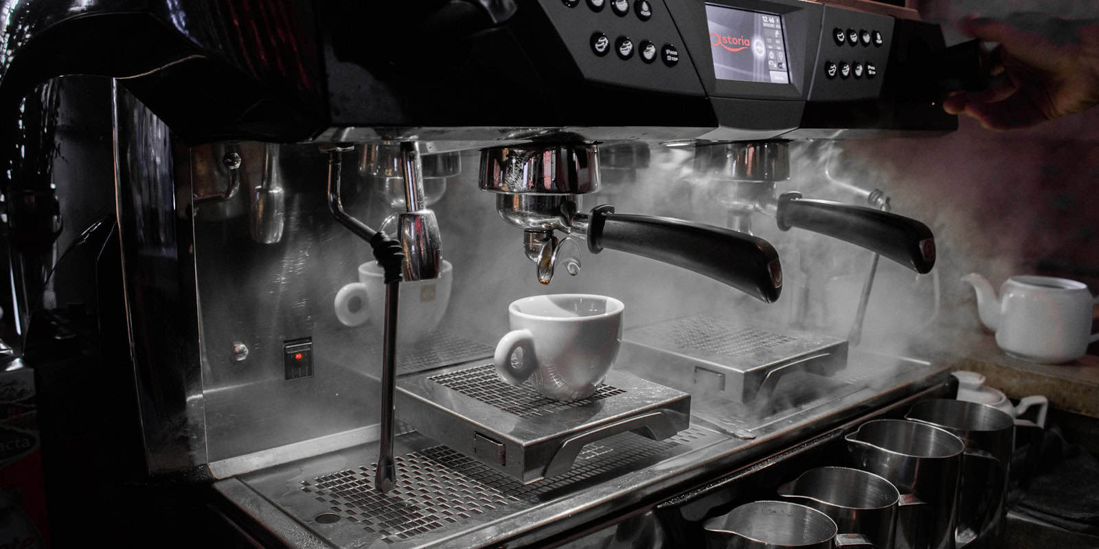 A professional espresso machine steaming and brewing coffee into a white cup - beann artisan coffee