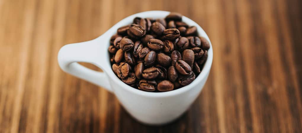 Beann artisan coffee beans in a white cup on a wooden table - beann speciality coffee
