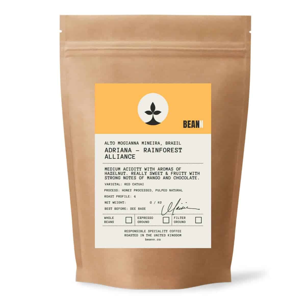 A brown paper bag of Bean brand coffee beans with a white and yellow product label - beann artisan coffee