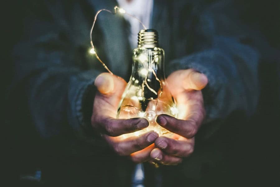 Holding a light bulb in hands - Top Digital Innovation Consultancy Guide - Photo by Riccardo Annandale | de Paula Consultants