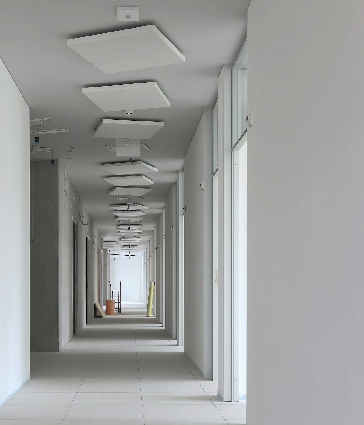 A spacious hallway characterized by white walls and a white ceiling, contributing to a well-lit and airy feel.