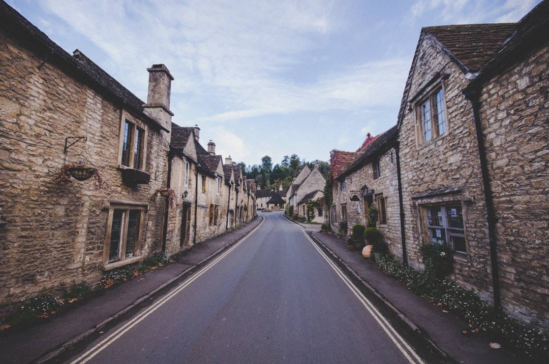 View up the high street to the market cross with Cotswolds cottages in Castle Combe Village, Wiltshire, UK β Doctor Thorne series location - Photo by Ivy Barn | Castle Combe England