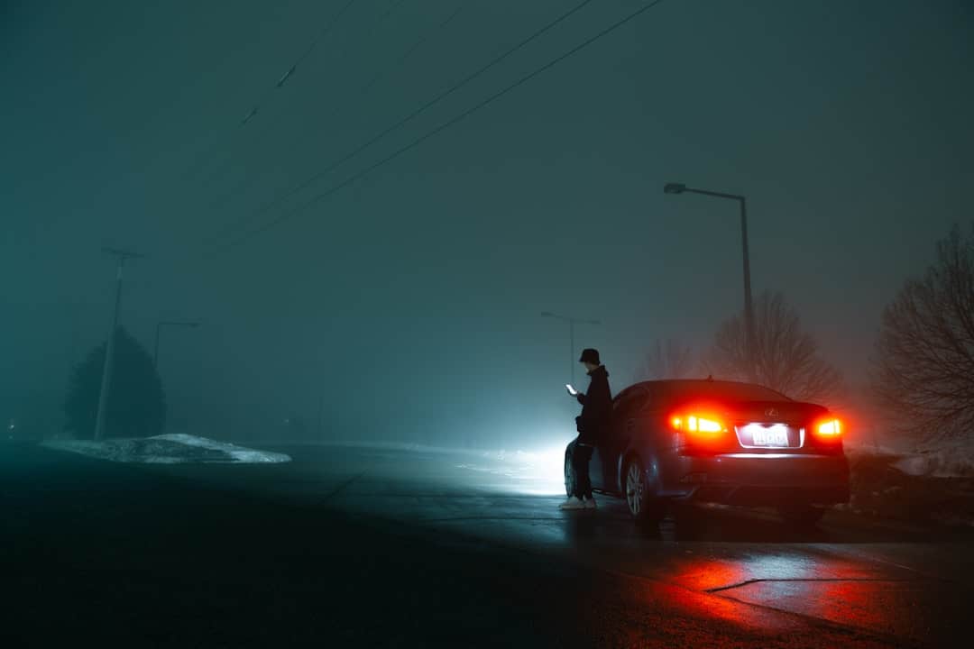 Car and figure on a foggy night – How to get to Castle Combe - Photo by Donny Jniag | Castle Combe England