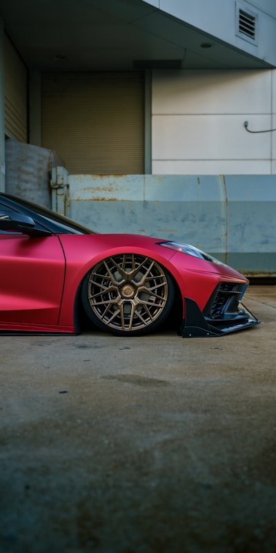 A sleek red sports car showcasing its stylish wheels, emphasizing speed and performance.