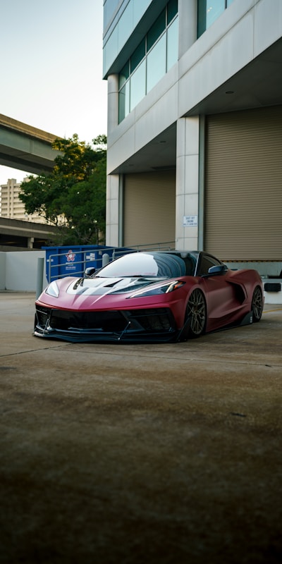 A red sports car with its doors open, showcasing its sleek design and vibrant color against a clear background.