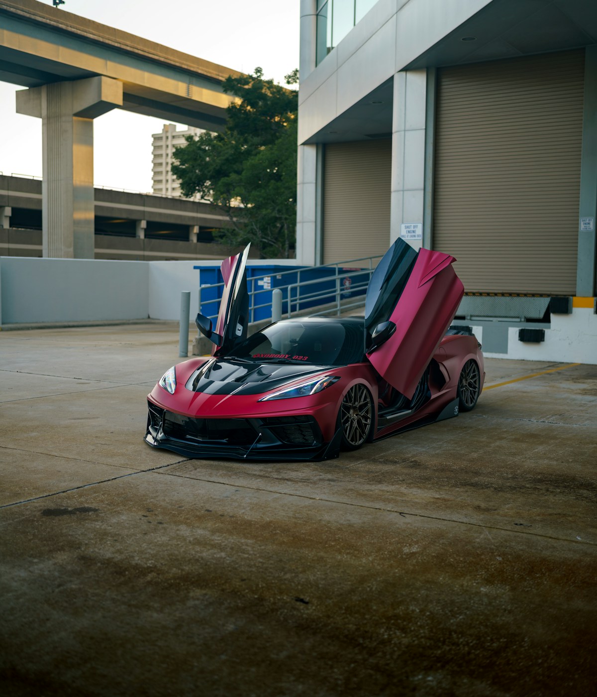 A red sports car with its doors open, showcasing its sleek design and vibrant color against a clear background.