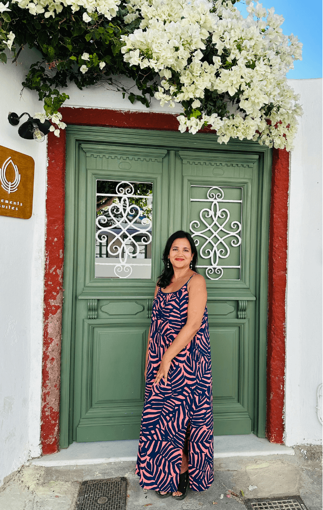 Meghna Patel before a green door with white bougainvillea