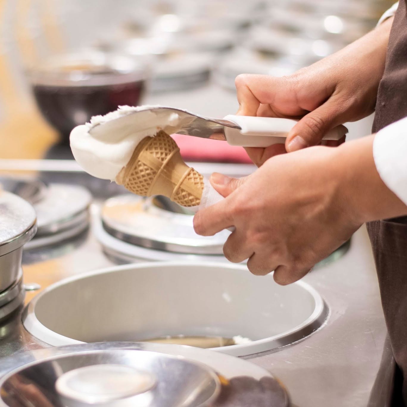 Artigiano che serve una pallina di gelato artigianale dal pozzetto al cono