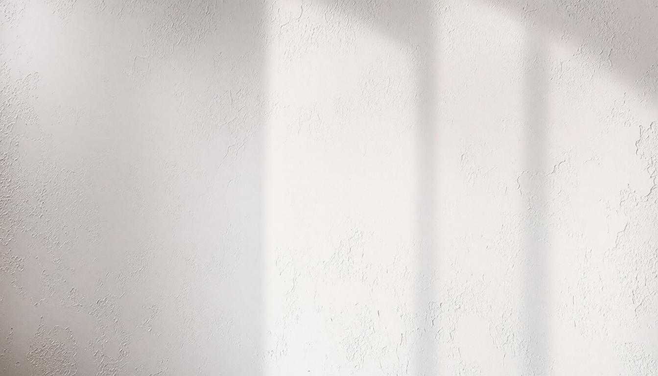 A white wall featuring a window and a single chair positioned nearby.