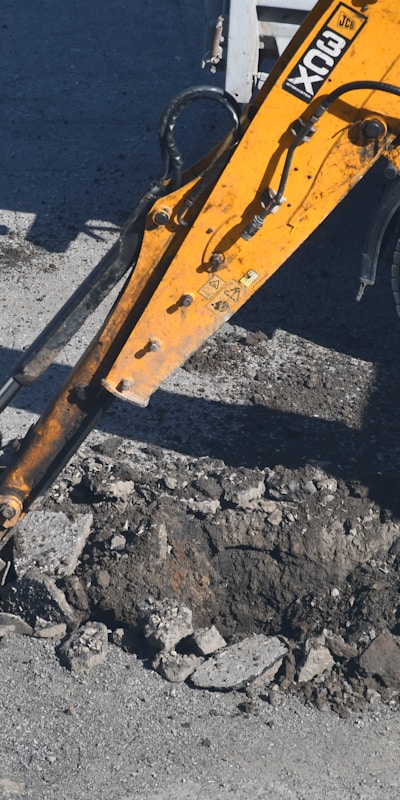 A close-up of a large excavator digging into the ground, showcasing its powerful arm and bucket in action.