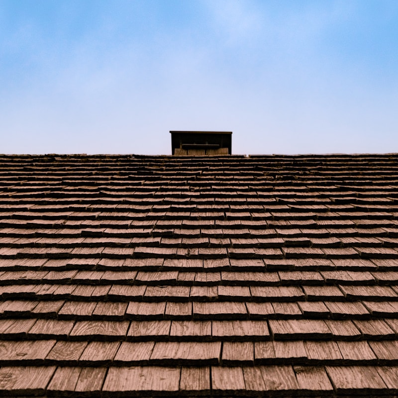 A roof featuring a chimney and a chimney stack against a clear sky.