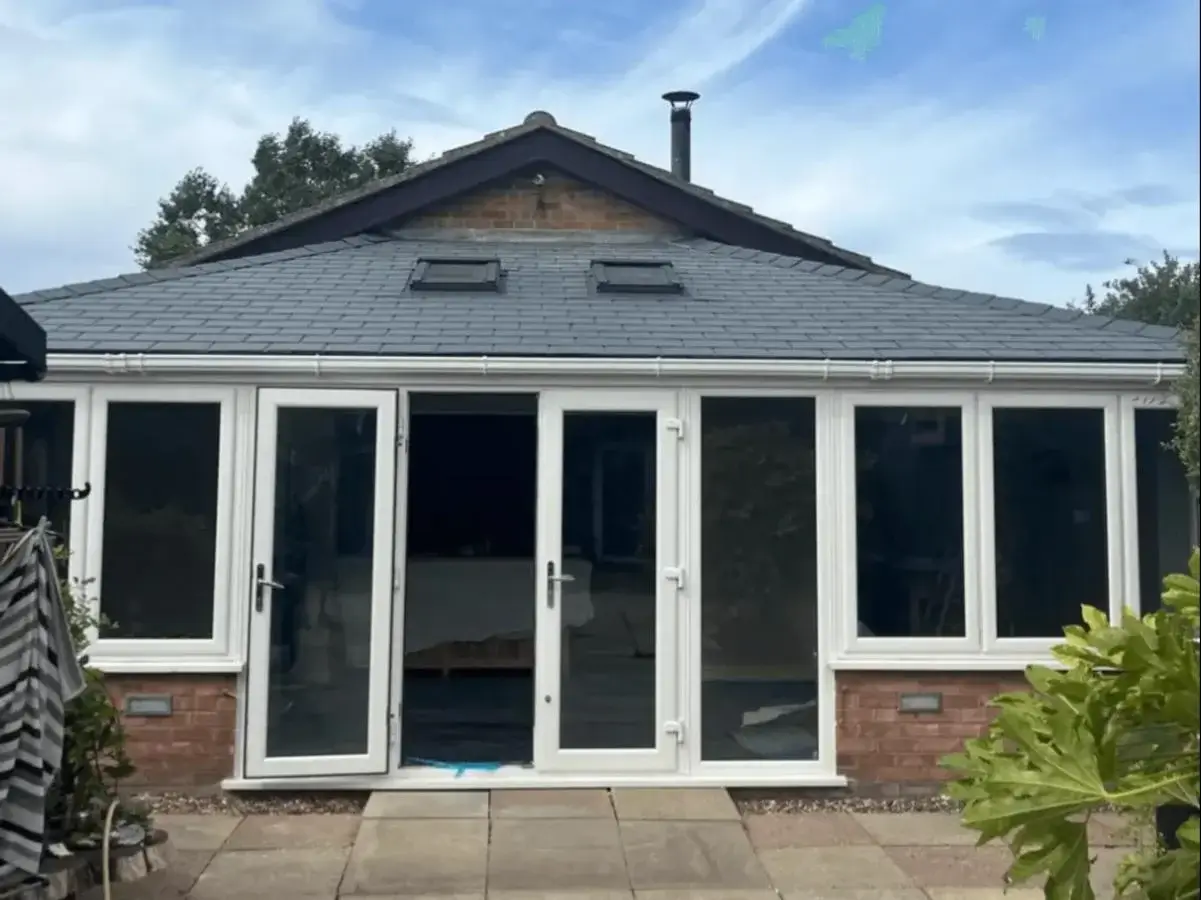 Completed slate-effect tiled solid roof conversion on a brick-based garden room conservatory with white uPVC doors by Norfolk Exterior Solutions.