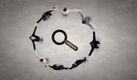 Desk with leather desk pad, walnut desk organizer, wireless keyboard and mouse, and porcelain mug.