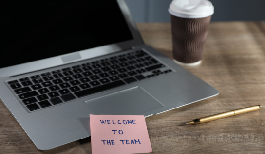 Desk with leather desk pad, walnut desk organizer, wireless keyboard and mouse, and porcelain mug.