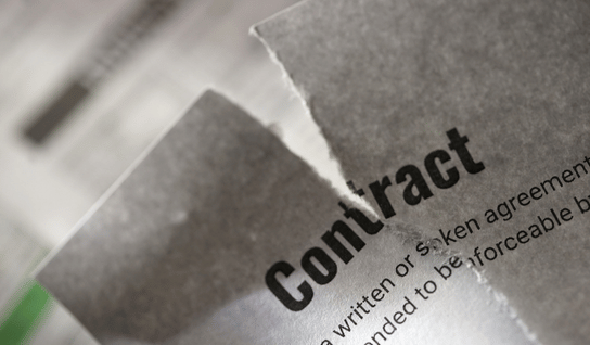 Desk with leather desk pad, walnut desk organizer, wireless keyboard and mouse, and porcelain mug.