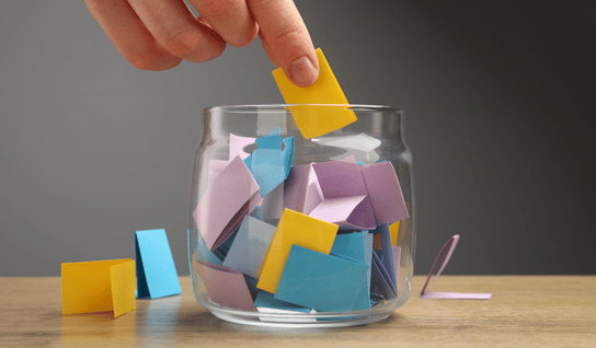 Wood table with porcelain mug, leather journal, brass pen, leather key ring, and a houseplant.