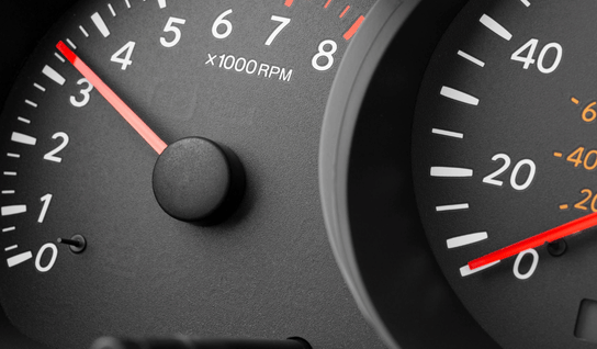 Wood table with porcelain mug, leather journal, brass pen, leather key ring, and a houseplant.