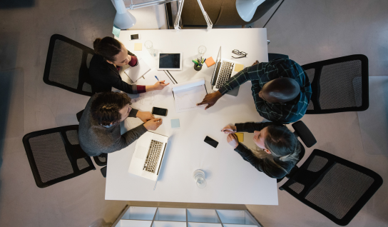 Desk with leather desk pad, walnut desk organizer, wireless keyboard and mouse, and porcelain mug.