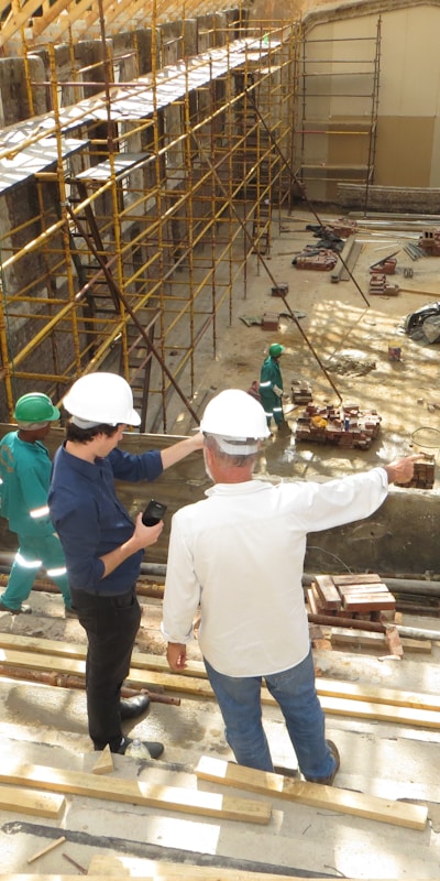 Construction workers collaborating on a busy construction site, wearing safety gear and operating machinery.