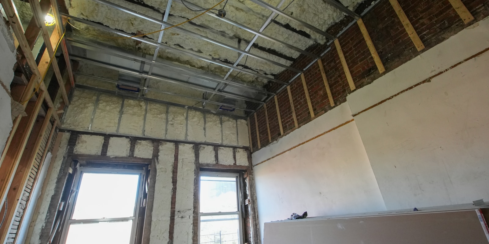A room featuring exposed insulation and newly installed drywall, indicating ongoing construction or renovation work.