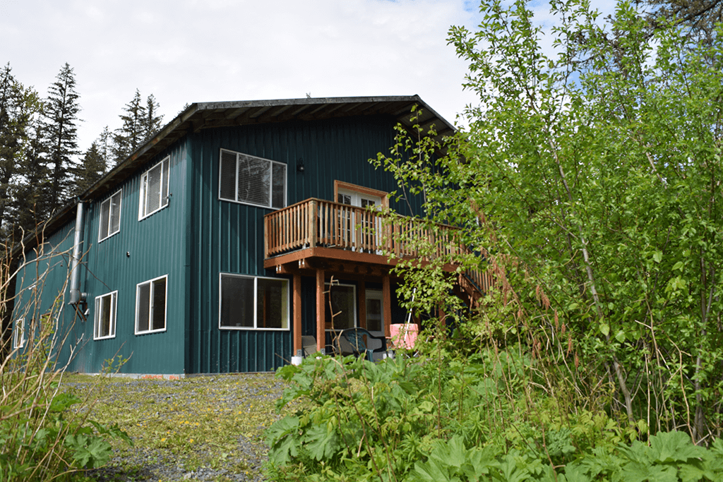 Wood table with porcelain mug, leather journal, brass pen, leather key ring, and a houseplant.