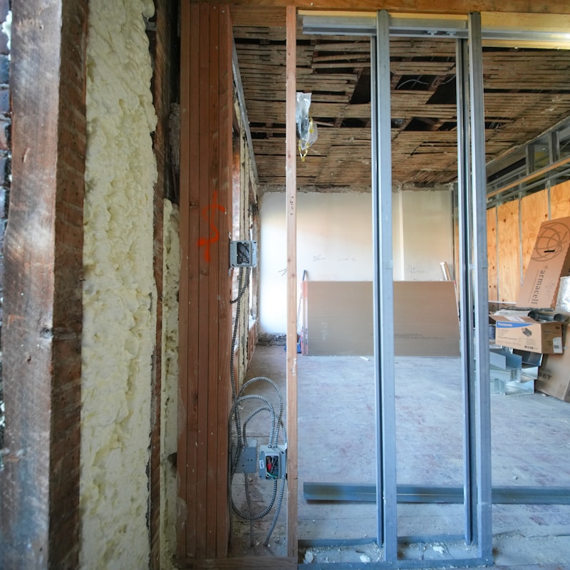 A construction site showing a room with an unfinished door and windows, highlighting ongoing building work.